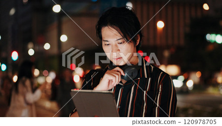 Creative, serious and man with tablet, night and video editor with ideas, headphones and project. Content creation, contemplating and Asian person with tech, post production and process in Japan 120978705