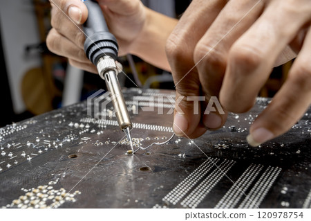 Man technician soldering a circuit board Man technician soldering a circuit board 120978754