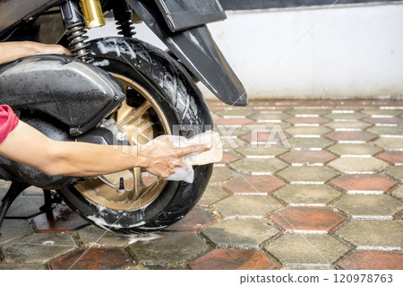 Professional worker hand washing the motorcycle with cleaning foam 120978763