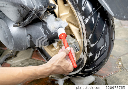 Professional worker hand washing the motorcycle with cleaning foam 120978765