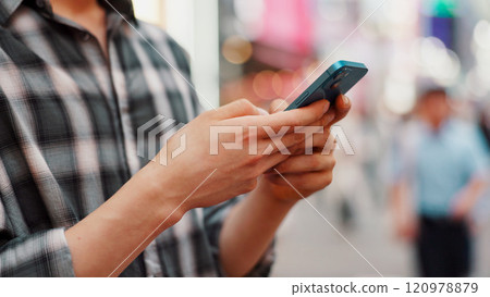Hands, phone and person typing in city to check text, social media or blog post on account in Japan. Closeup, mobile or online outdoor for communication, notification or download chat app on internet 120978879