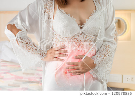 A woman is holding and rubbing her abdomen due to acute abdominal pain. 120978886
