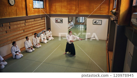 Dojo, master and demonstration of Aikido training in class with wood sword Japanese martial arts and fight exercise in studio. Learning, sport and bamboo weapon with people and strike practice above Dojo, master and demonstration of Aikido training in class with wood sword Japanese martial arts and fight exercise in studio. Learning, sport and bamboo weapon with people and strike practice above 120978945