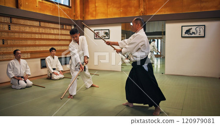 Dojo, class and mentor in Aikido training in gym with wood sword Japanese martial arts and fight exercise in wellness studio. Learning, sport and weapon with people and strike practice for defence 120979081