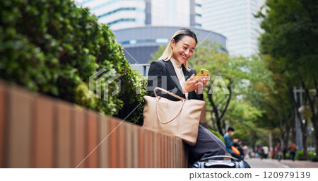 Business woman, phone and luggage on travel in city with contact, happy and low angle on fence in street. Person, smartphone and corporate lawyer with booking taxi, networking and baggage in Japan 120979139