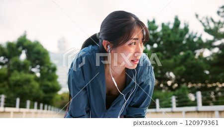 Tired, woman and fitness with earphones in city from sport exercise, marathon training and listen to music. Athlete, fatigue and break of cardio workout, physical recovery and podcast on Japan bridge Tired, woman and fitness with earphones in city from sport exercise, marathon training and listen to music. Athlete, fatigue and break of cardio workout, physical recovery and podcast on Japan bridge 120979361