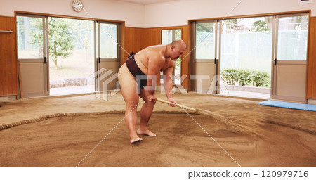 Broom, dohyo and sand with Sumo wrestler sweeping arena in mawashi, getting ready for competition. Cleaning, preparation and start with Japanese person for culture, heritage or martial arts tradition 120979716