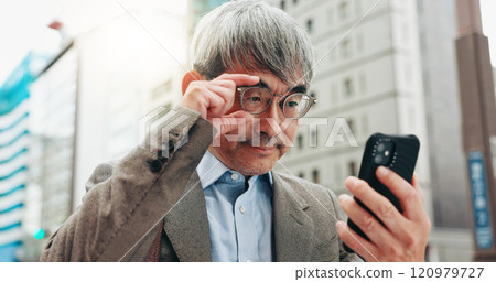 Serious, travel and businessman with smartphone, city and research for real estate, listing and outdoor. Glasses, reading and competition analysis with mobile, morning and mature person in Japan 120979727