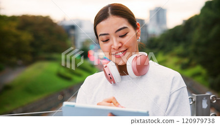 Japanese woman, smile and tablet in city for copywriting, reading article and publishing process. Female writer, headphones and review blog with newsletter, editing update and project on Japan bridge 120979738