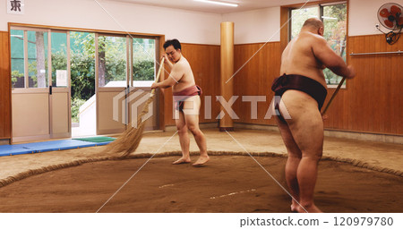 Ceremony, broom and dohyo with Sumo wrestler people sweeping sand in mawashi, getting ready for competition. Cleaning, prepare and start with men in Japan for culture, heritage or martial arts Ceremony, broom and dohyo with Sumo wrestler people sweeping sand in mawashi, getting ready for competition. Cleaning, prepare and start with men in Japan for culture, heritage or martial arts 120979780
