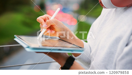 Hands, person and writing on tablet in urban for copywriting, article manuscript and publishing post. Writer, headphones and pen with newsletter blog, editing update and story project on Japan bridge 120979858