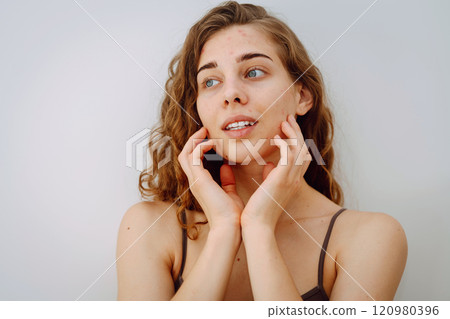 Close-up of a cute woman with problem skin looking in the mirror. Dermatology concept, allergy. Close-up of a cute woman with problem skin looking in the mirror. Dermatology concept, allergy. 120980396
