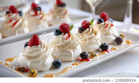 pavlova is topped with whipped cream, an assortment of fresh berries (strawberries, blueberries, raspberries), and a passion fruit drizzle, enhancing the luxurious and inviting ambiance 120980914