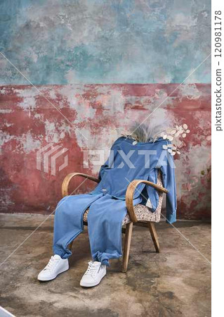 Blue Hues: Jumpsuit and Armchair Against a Textured Wall Blue Hues: Jumpsuit and Armchair Against a Textured Wall 120981178
