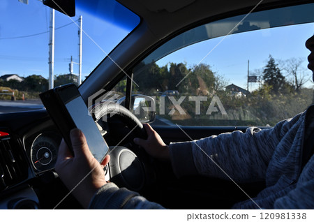 Driving while looking at a smartphone, using a smartphone while driving, dangerous driving Driving while looking at a smartphone, using a smartphone while driving, dangerous driving 120981338