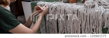 Woman weaves home Handmade decor from cotton thread macrame. Macrame panel creating process. Banner 120981575