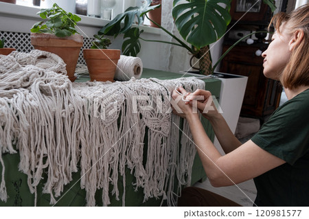 Woman weaves home Handmade decor from cotton thread macrame. Macrame panel creating process. 120981577
