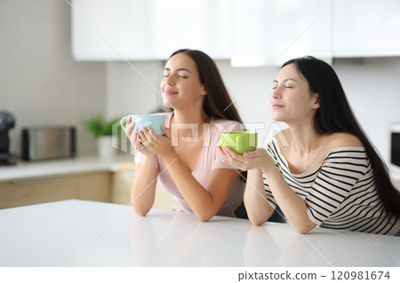 Two women smelling coffee or breathing in the kitchen Two women smelling coffee or breathing in the kitchen 120981674