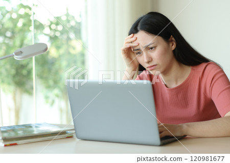 Worried asian woman checking laptop in a room 120981677