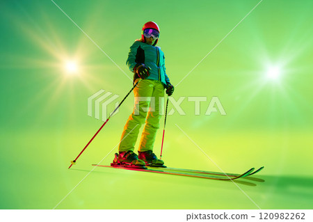 Female skier smile and confident pose, holding poles slightly angled, fully illuminated by the studio's neon green glow. Female skier smile and confident pose, holding poles slightly angled, fully illuminated by the studio's neon green glow. 120982262