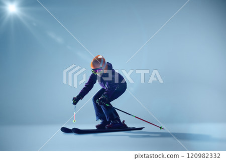 Young woman, sport lover, kier crouches in action pose, ready to glide, against gradient blue studio background. Young woman, sport lover, kier crouches in action pose, ready to glide, against gradient blue studio background. 120982332