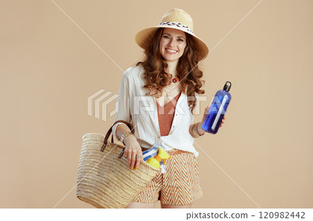 smiling stylish woman in blouse and shorts isolated on beige 120982442