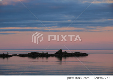 Pink sky over Lake Vanern and a rock formation in Vita Sannar, Sweden. 120982732