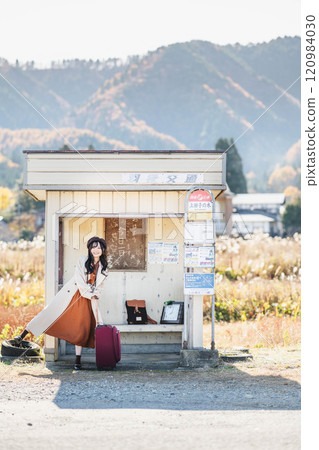 A young woman waiting for a bus at a bus stop. Photo courtesy of Ugo Kotsu. 120984030
