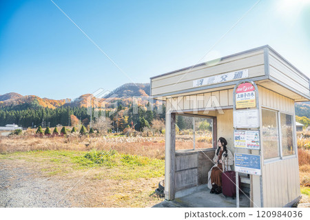 A young woman waiting for a bus at a bus stop. Photo courtesy of Ugo Kotsu. 120984036