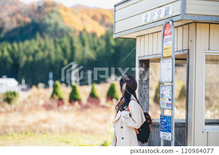 A young woman waiting for a bus at a bus stop. Photo courtesy of Ugo Kotsu. 120984077