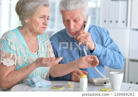 An elderly couple is sick and takes medication at home 120984261