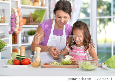 Mother and daughter preparing salad with daughter in the kitchen Mother and daughter preparing salad with daughter in the kitchen 120984301