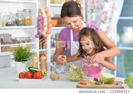 Mother and daughter preparing salad with daughter in the kitchen Mother and daughter preparing salad with daughter in the kitchen 120984317