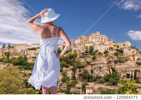 Woman in summer dress on vacation looking at the village of Gordes in Luberon, Provence, France 120984373