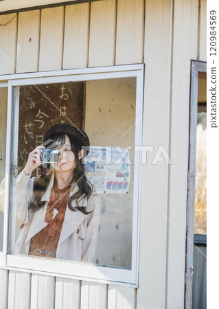 A woman taking pictures while waiting for the bus at a bus stop. Photo courtesy of Ugo Kotsu. 120984569