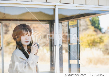 一位女士在公車站等車時用相機拍照 攝影由 Ugo Kotsu 提供。 一位女士在公車站等車時用相機拍照 攝影由 Ugo Kotsu 提供。 120984570