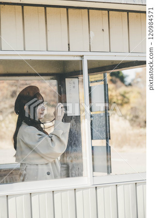 A woman taking pictures while waiting for the bus at a bus stop. Photo courtesy of Ugo Kotsu. A woman taking pictures while waiting for the bus at a bus stop. Photo courtesy of Ugo Kotsu. 120984571