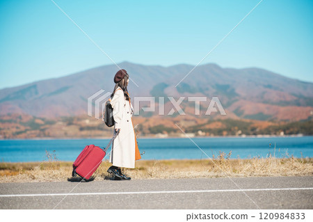 Women's trip: A young woman walking under the blue sky with a carry bag 120984833