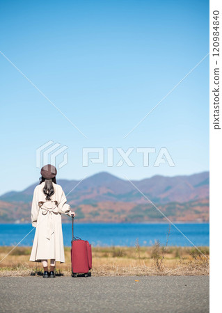 Women's trip: A young woman walking under the blue sky with a carry bag Women's trip: A young woman walking under the blue sky with a carry bag 120984840