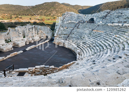 Ancient ruins of historical Patara city with old greek amphitheater and sunny Mediterranean landscape with distant hills. History and adventure on summer Turkish holidays. Lycian way, Antalya, Turkey 120985262