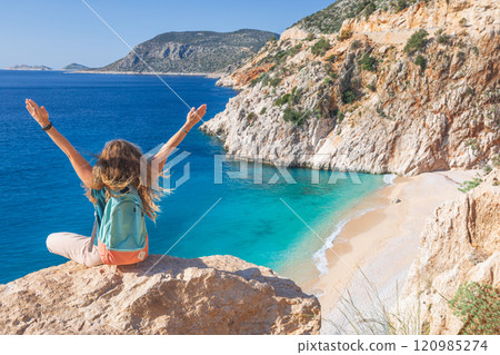 Young woman with backpack looking out over Kaputas beach, Lycia coast. Summer day walk by Lycian way at family vacation in Mediterranean Sea, Kas, Antalya region, Turkey 120985274