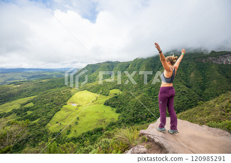 Woman standing on a mountaintop with arms raised, enjoying breathtaking green landscape Soldados sebold, Brazil. Freedom, adventure in serene outdoor environment, perfect for hiking and mindfulness. Woman standing on a mountaintop with arms raised, enjoying breathtaking green landscape Soldados sebold, Brazil. Freedom, adventure in serene outdoor environment, perfect for hiking and mindfulness. 120985291