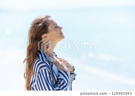 relaxed elegant woman on ocean shore enjoying tranquility 120985943