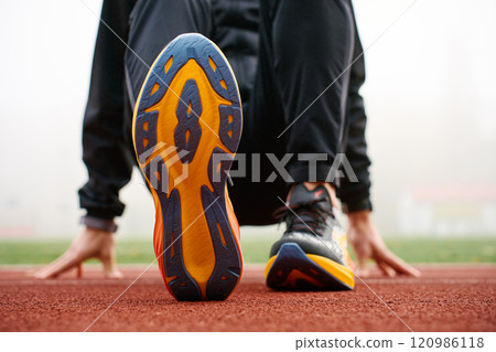 Athlete wearing modern running shoes walking on stadium track 120986118