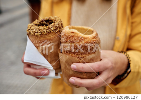 Woman holding two traditional chimney cakes at street of Prague, Czech Republic 120986127