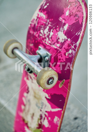 Used pink skateboard against stone wall in urban setting Used pink skateboard against stone wall in urban setting 120986133