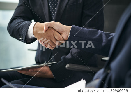two asian businessmen shaking hands in office 120986659
