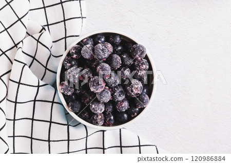 Close up of frozen blackcurrants in bowl on table top view 120986884
