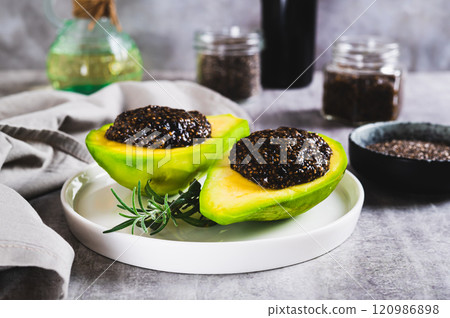Black chia caviar in avocado halves on a plate on the table 120986898