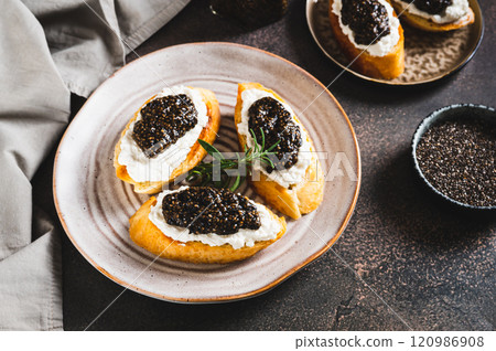 Bruschetta with cream cheese and black chia caviar on a plate on the table Bruschetta with cream cheese and black chia caviar on a plate on the table 120986908